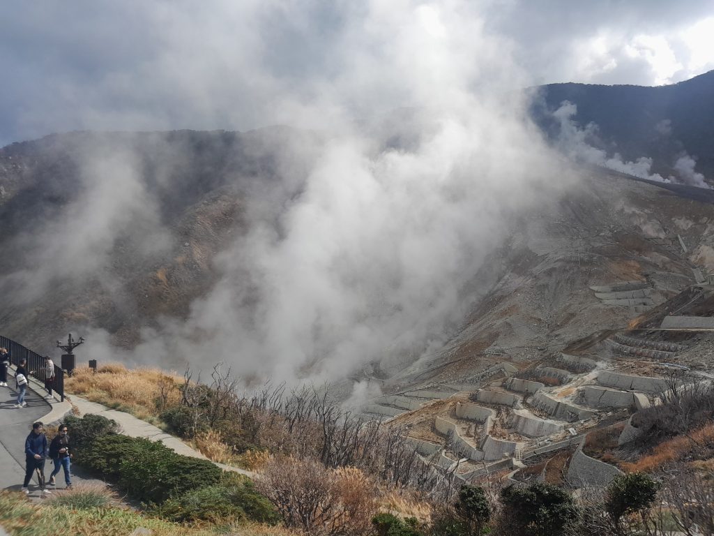 Paysage volcanique d'Owakudani à Hakone avec des fumerolles de soufre s'échappant de la montagne sous un ciel bleu, Japon