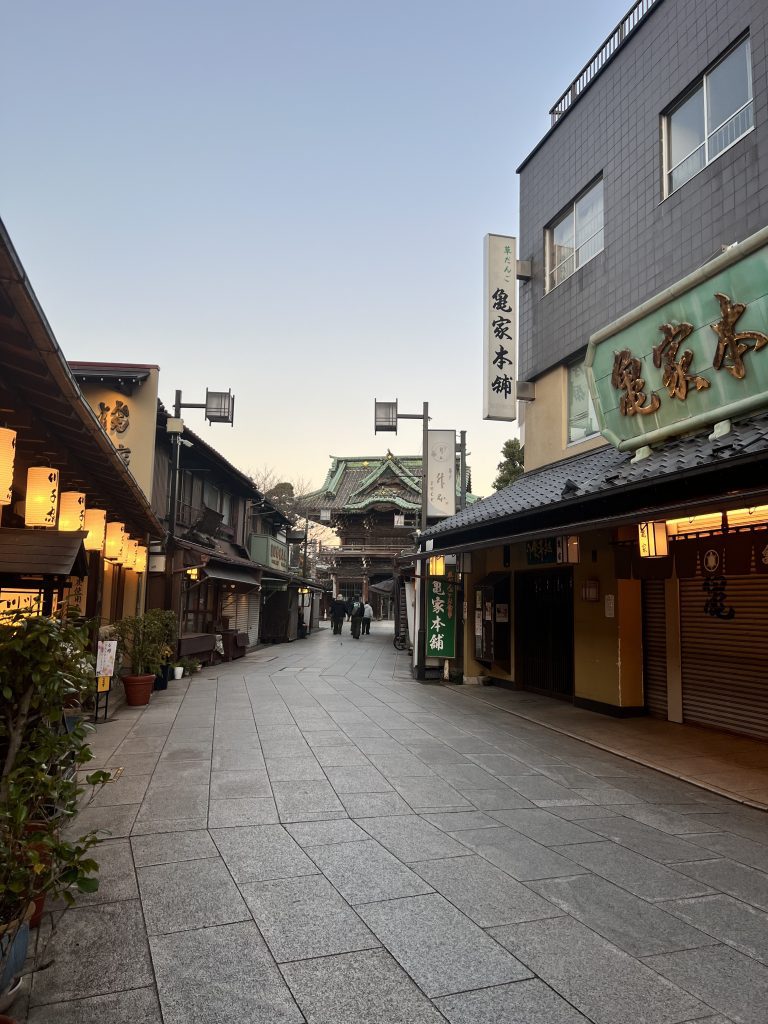 Ruelle commerçante traditionnelle pavée menant au temple Taishakuten à Shibamata, Tokyo, avec lanternes japonaises et enseignes en bois.